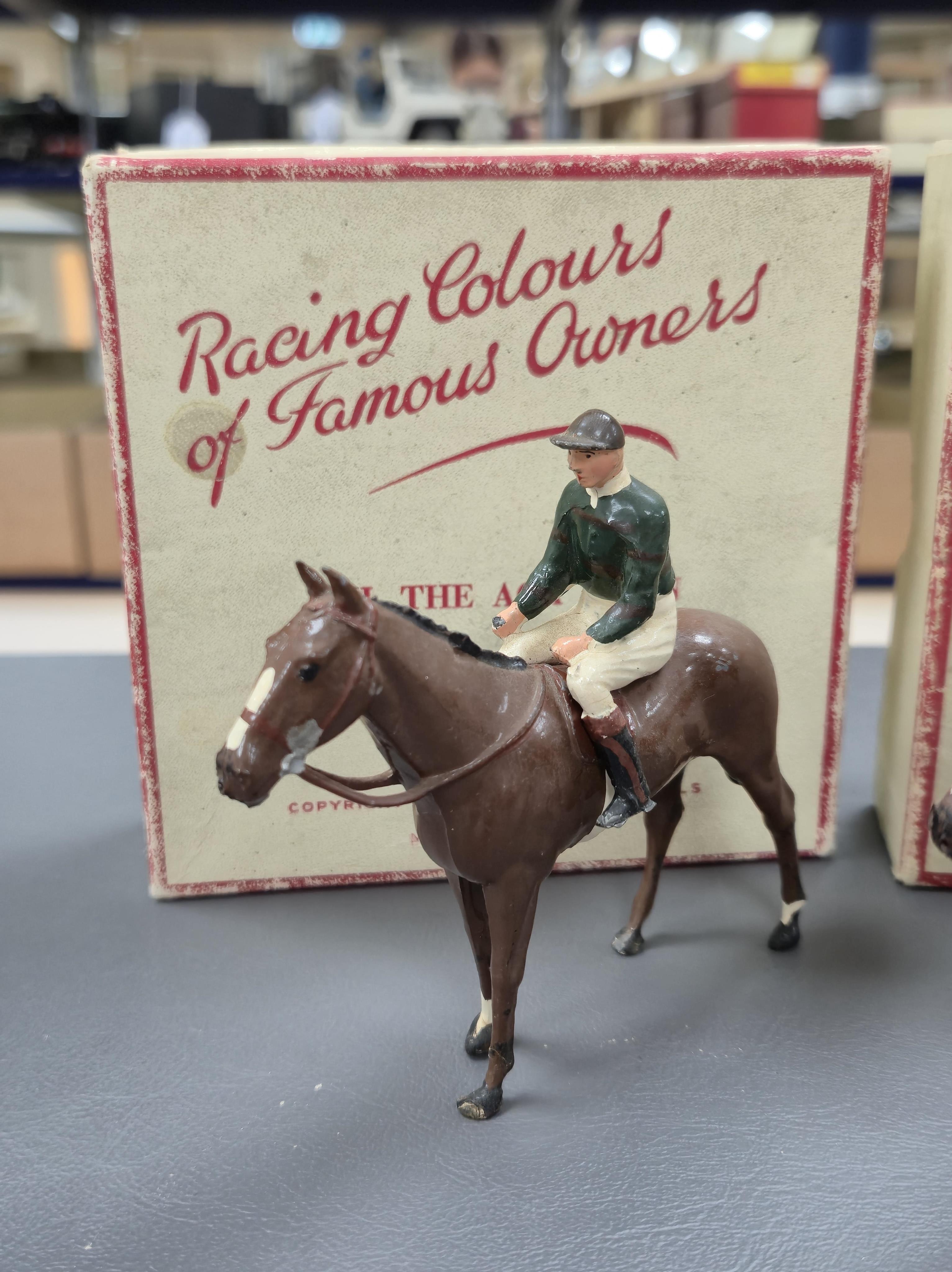 Two boxed Britains Racing Colours of Famous Owners series lead mounted figures; H.M. The Queen - rider in purple and brown jersey with gold frogging on a brown horse, and H.H. The Aga Khan - rider in dark green jersey on